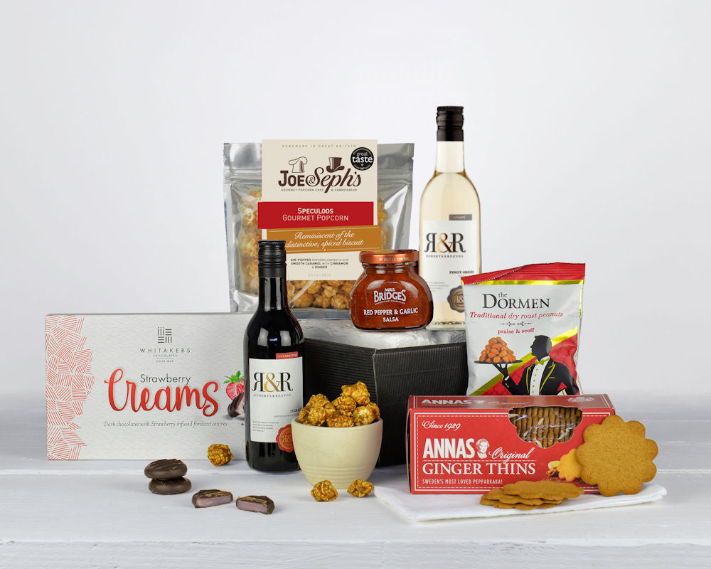 two little bottles of wine, popcorn, biscuits, chocolates an snacks in a black gift tray
