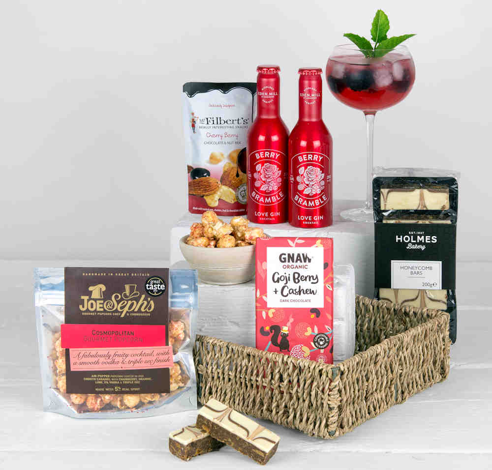 2 Berry Cocktails, popcorn, chocolate bar, tasty honeycomb traybakes and cherry berry chocolate nut mix in a seagrass gift tray