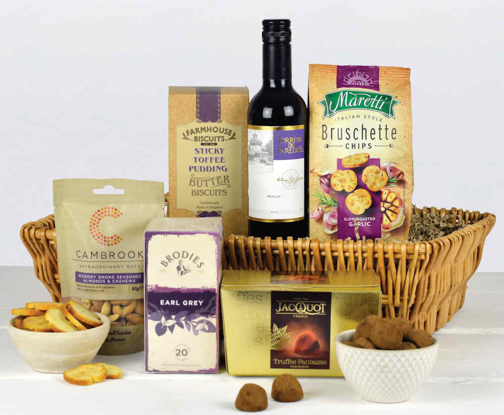Wicker Tray with a bottle of red wine, tea, biscuits, french truffle chocolates and other savoury snacks.