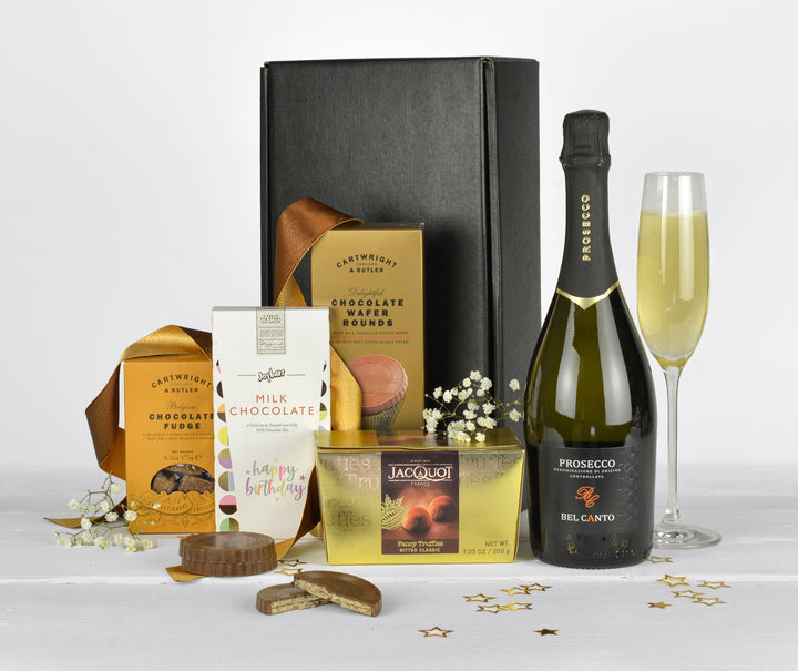 A bottle of prosecco, french chocolate truffles, chocolate wafer biscuits, chocolate fudge and a happy birthday chocolate bar in a black gift box